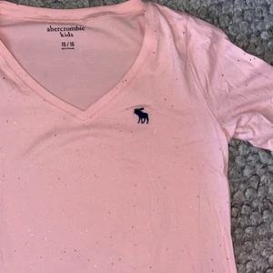 Abecrombie & fitch långärmad - Jättesöt v-ringad långärmad tröja från abecrombie and fitch. Ljusrosa och glittrig. Är i storlek 15/16y vilket motsvarar xs-s. Knappt använd.