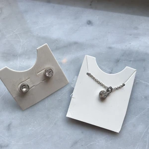 Matchande örghängen och halsband - Matchande silvriga fina små örhängen och halsband med en liten berlock. Oanvända och köpta på glitter💕köparen står för frakt!