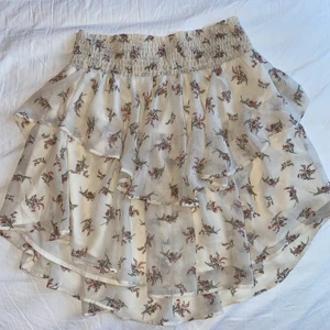 Blommig kjol  - Blommig beige kjol från Gina tricot. Snygg och ”flowig”, går ungefär till mitten av låren, stretchig. Använd bara ett par gånger så är i ett väldigt bra skick!