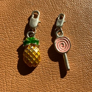 Berlocker till smycken - Två supersöta berlocker att sätta på valfria smycken. Den ena föreställer en ananas och den andra en klubba. Båda är i ett silvrigt material, troligtvis inte riktigt silver då jag inte kan hitta en stämpel. Inköpta i Frankrike för ett antal år sedan. Oanvända och i ett mycket bra skick. Kan sättas på ett armband eller halsband men kan även göras om för att passa det ändamål du vill ha dom till. 20kr styck. GRATIS FRAKT!!