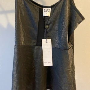 Glittrigt linne oanvänd VeroModa - Oanvänt linne från vero Moda som har kramande effekt på övre delen och flare vid nedre delen. Köptes för ett tag sen så den finns ingenstans att köpa i dagsläget, har som ett när i mitten väldigt snyggt och trendigt. Har fler bilder om det önskas. Den är inte så lång och sitter som en normal S, jag är en större M och den passar inte därav säljer jag den.