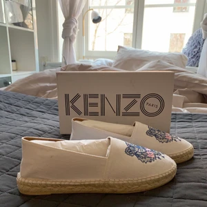 Kenzo espandrillos i storlek 39 - Ett par helt oanvända, vita, tiger canvas espandrillos i storlek 39. Perfekta och enkla skor att ha på sommaren. Säljer dem för 1100 kr, (orginalpriset ligger runt 1800 kr) men priset kan diskuteras. Kan mötas upp i Sthlm eller skicka på posten<3