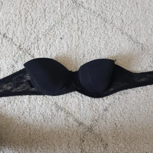 Oanvänd strapless bh - Oanvänd svart strapless bh. Banden som går runt är i spets och har 3 hakar.
