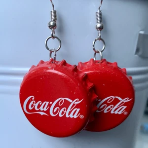 coca cola örhängen  - egengjorda örhängen av coca cola kapsyler. unika och har själv fått många komplimanger för de. de är lite tyngre eftersom det är kapsyler men det är inget man tänker på under dagen. 50kr inklusive frakt. ❗️INTE NICKELFRIA❗️om du har några frågor är det bara att fråga på:)