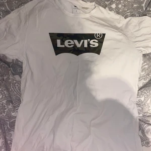 Levis t- shirt - En vit Levis t- shirt med kamouflage tryck i st M. Är använd rätt mycke men har tagit bra hand om den och den är fin i skicket, frakt tillkommer 66kr