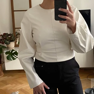 Topp från nakd - Topp i vit skinnimitation, lite "ballongärmar".  Aldrig använd, prislappen är kvar. Går även att knyta bandet framåt om man vill deeeeeet🤎