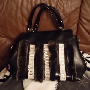 Väska - En helt ny väska i äkta läder med pälsdetaljer och glitter på framsidan. Rejält läder som håller i längden och många olika fack på insidan.