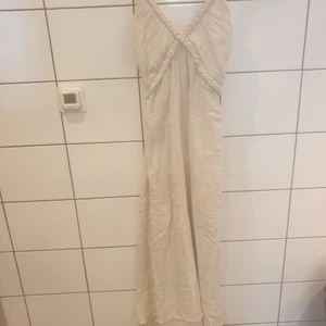 Naturvit linneklänning med flätade detaljer  - Lång klänning i naturvit färg med flätade detaljer. Aldrig använd och köpt för säkert 10 år sedan. 