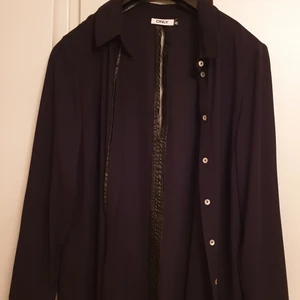 Svart skjorta - Svart skjorta. Rak modell. Öppen i ryggen, blankt hudvänligt tyg. Använd en gång