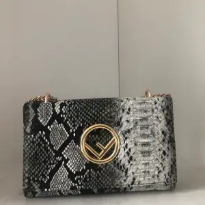 Svart vit väska med orm mönster och guld detaljer 
