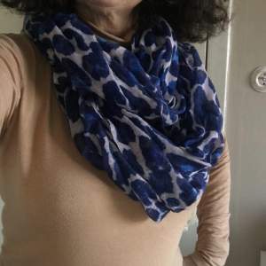 Blålila scarf i leomönster i bomull (70%) och polyester (30%). Utlagd är den 100x85cm, dubbelvikt. Tunn och skön!