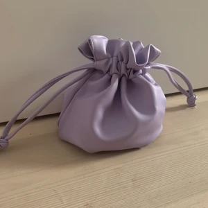 Liten unik handväska i pastellila  - Superfin, unik lila handväska som liknar en liten knytpåse, längre axelband tillkommer! Oanvänd! Så gott skick💜 fråga om mått eller fler bilder om du undrar!💜 frakt tillkommer 