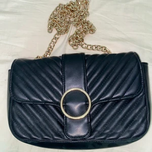 Svart & guldig handväska - Säljer denna handväskan då jag har så många! Den är använd men har inga synliga skråmor. Köparen står för frakten och jag möts ej upp❤️ hoppas någon annan kan glädja sig av denna!