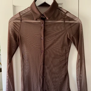 Mesh skjorta - En superfin brun genomskinlig skjorta i brunt mesh matrial den är lite 70 tals inspirerad och liknar den skjortan som kendall jenner har haft.  Den är köpt här på plick men säljer den då den var för liten för mig