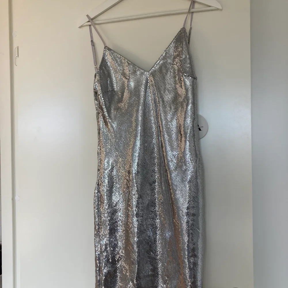 Oanvänd silvrig klänning med paljetter från Linn Ahlborgs kollektion från nakd, deras waterfall dress med superfint fall i ryggen🤩 alla lappar sitter kvar, skicka pm för egna bilder🤍 i storlek 34 (xs/s) . Klänningar.