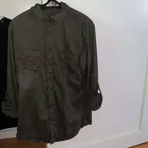 En skjorta i militärgrön aktig färg från Dressman. Använd några gånger men är i fint skick. Denna är i storlek M och är Slim fit modell.