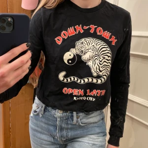 Urban Outfitters tröja - Säljer denna coola svarta croppade tröja ifrån Urban Outfitters, använd ett fåtal gånger! Man kan dra åt tröjan längst midjan som visas på bild 3🖤🖤