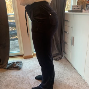 Juicy Couture byxor  - Mörkblåa Juicy Couture byxor i storlek M köpta på NK. Nyköpta, ca 2 månader gamla och nästan oanvända. Säljs pga fel storlek. Byxorna är i nyskick med underbart skönt material. Byxorna är modellen med fickor.