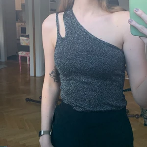 Glittrigt oneshoulder-linne - Säljer detta snygga oneshoulderlinne från Nelly. Oanvänt. Storlek S.