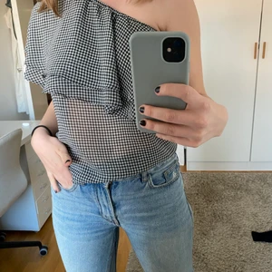 Cool offshoulder topp i rutmönster - Supercool topp i tunt och skönt tyg. Rutigt mönster som ser nästan grått ut. Volanger i lager över den övre delen.