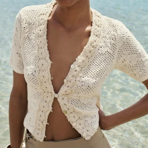 Stickad topp - Säljer en söt beige stickad kofta från Zara med korta ärmar och v-ringning. Jag har endast använt den en gång (testat en gång) alltså är den i nytt skick. Jag säljer den då den inte kommer till användning, kontakta mig om ni har frågor!