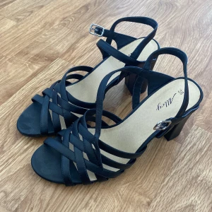 Svarta sandaler med klack - Snygga svarta sandaler med öppen tå och blockklack. De har flera remmar som korsar varandra och en justerbar spänne runt ankeln. Perfekta för en stilren look. Oanvänd💕