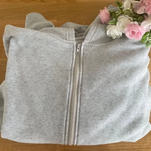 Grå hoodie med dragkedja - Säljer en stilren grå hoodie med dragkedja framtill. Tröjan har en klassisk design med huva och fickor, perfekt för en avslappnad look. Passar bra till både jeans och mjukisbyxor.