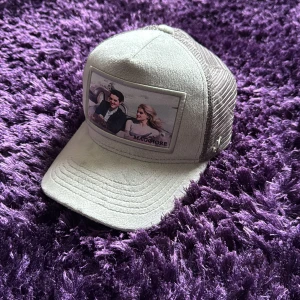 Grå keps med nätpaneler - Snygg grå keps från Maggiore med nätpaneler för extra ventilation. Framsidan har en tryckt bild och text. Perfekt för en avslappnad stil.