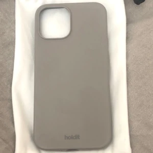Grått mobilskal från Holdit - Säljer ett stilrent grått silikon skal från Holdit till iPhone 12 PRO Max. Finns en liten spricka i plasten innanför silikonet och ett ställe där silikonet gått sönder (finns bild). Nypris 199kr