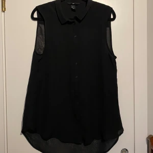 Svart ärmlös blus! Storlek 40! Aldrig använd!  - Snygg svart ärmlös blus med krage och knappar framtill. Perfekt för en stilren look. Materialet är lätt och luftigt, vilket gör den bekväm att bära.