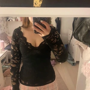 Svart spetsblus från Gina Tricot - Säljer en elegant svart spetsblus från Gina Tricot. Blusen har långa ärmar och en v-ringad design som ger en stilren look. Perfekt för att lägga till en touch av elegans till din outfit. Kontakta mig för mer info!