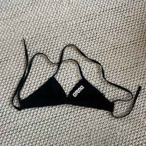 Svart bikiniöverdel från Arena - Snygg svart bikiniöverdel från Arena med knytband. Storlek UK 26 (se bild) och i bra skick. 