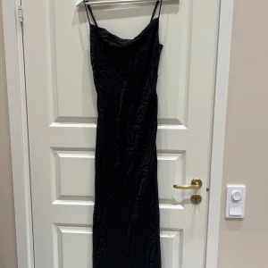 Svart långklänning med mönster från Gina Tricot - Snygg svart långklänning från Gina Tricot med tunna axelband och ett subtilt mönster. Perfekt för en elegant kvällslook. Klänningen har en smickrande passform och är tillverkad i ett mjukt material.❤️