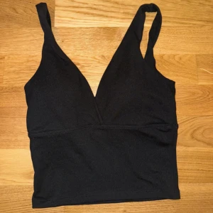 Svart v-ringad linnetopp - Snygg svart linnetopp med djup v-ringning och breda axelband. Perfekt för en stilren look.