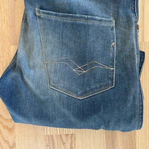 Blå jeansbyxor från Replay - Snygga blå jeansbyxor från Replay i modellen Anbass. De har en klassisk femficksdesign med en diskret logga på fickan och en dragkedja. Perfekta för en avslappnad stil.