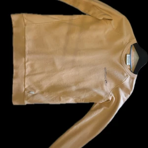 Orange  tröja från Scotch & Soda - Snygg orange tröja från Scotch & Soda med rund halsringning och långa ärmar. Tröjan har en subtil logga på bröstet i färgglada bokstäver. Perfekt för en stilren och avslappnad look.