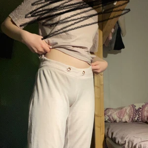 Vit/Rosa mjukisbyxor - Säljer ett par bekväma vit/Rosa mjukisbyxor med elastisk midja och knappdetaljer. Perfekta för en avslappnad dag hemma.