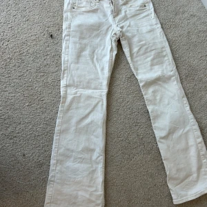 Vita bootcut jeans - Snygga vita bootcut jeans i denim. De har en klassisk femficksdesign och knappar framtill. Perfekta för en stilren look.