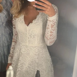Vit spetsklänning från Bubbleroom - Säljer en elegant vit spetsklänning från Bubbleroom. Klänningen har en v-ringad design med långa ärmar och ett vackert blommigt mönster. Använt en gång. Perfekt för skolavslutning💕🌸