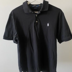 Ralph Lauren pikétröja - Polo Ralph Lauren pikétröja Storlek: M (Passar perfekt M och tight L) | Färg: Svart Klassisk modell, i fint skick – inga fläckar eller slitage. Kvalitativ och tidlös, passar både till vardags och finare tillfällen.✨👕  Snabb leverans 🚚 och extra bilder får du gärna fråga om!