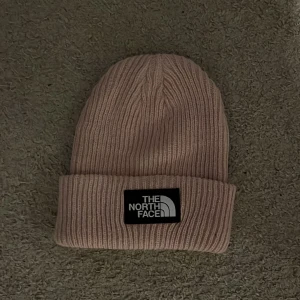 Riktigt nice rosa The north face mössa - Säljer en fresh snygg rosa The North Face mössa. Denna är riktigt snygg på tjejer och även på killar. Den är använd ett fåtal gånger och skicket är riktigt bra. Skulle rekommendera denna prudukt till nästan alla eftersom den passar till allt. Nypris= 400kr, Mitt pris=75kr!  Om ni undrar något är det bara att skriva😊.                                     m.v.h///// Avn Closet