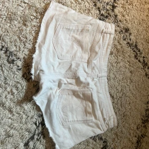 Vita jeansshorts  - Snygga vita lågmidjade jeansshorts med fransiga kanter och ficksdesign. 