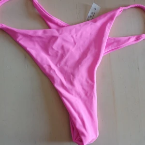 Rosa bikiniunderdel - Snygg rosa bikiniunderdel med enkel design och smala band. Perfekt för soliga dagar på stranden eller vid poolen. Den har en klassisk passform som ger en stilren look.