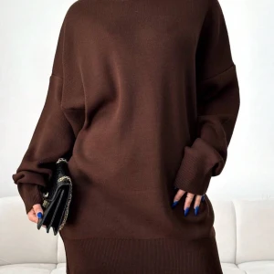 Brun stickad klänning - Säljer en mysig brun stickad klänning med långärmad design. Den har en loose passform och ribbade detaljer vid ärmslut och nederkant. Använd 1-2 gånger. Onesize