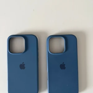 Blå mobilskal från Apple 16 PRO - Säljer två snygga blå mobilskal från Apple. Skalen har en stilren design med Apple-loggan på baksidan och är gjorda för att passa perfekt till din iPhone. Perfekt för att skydda din telefon med stil!