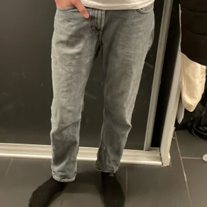 Grå jeans från Dressmann - Snygga grå jeans från Dressmann med en klassisk straight fit. Perfekta för en avslappnad stil. De har en traditionell femficksdesign och en bekväm midwaist. Passar bra till både t-shirt och skjorta.