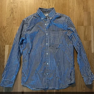 Rutig skjorta från GAP - Snygg rutig skjorta från GAP i blått och vitt. Skjortan har långa ärmar och knappar framtill. Perfekt för en stilren look.