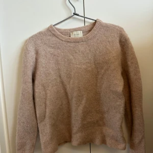 Beige stickad tröja från Neo Noir - Mysig beige stickad tröja från Neo Nior i färgen gammel dags rosa. Tröjan har långa ärmar och ribbade kanter vid ärmslut och nederkant. En stilren och enkel design som passar till det mesta. Står ingen storlek men passar alla som har storlek Xs