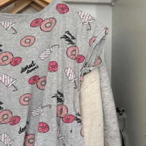Grått nattlinne med donuts och milkshakes från Lindex - Säljer ett grått nattlinne från Lindex med gulligt tryck av rosa donuts, milkshakes och texten 'donut dreams'. Nattlinnett har korta ärmar och är tillverkad i mjuk bomull. Perfekt för dig som gillar roliga mönster och bekväma plagg!