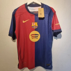 Barcelona Hemmatröja 24/25 - Player Edition L NY Nike Original - Player Edition matchtröja 24/25. Identisk till årets hemmatröja, samma premiumtyg. Storlek L                                                         https://www.unisportstore.se/fotbollstroejor/barcelona-hemmatroeja-202425-vapor/369000/        där den är slutsåld men kostade 1299kr eller på barca shop   https://store.fcbarcelona.com/products/fc-barcelona-match-home-bshirt-24-25?competition=ucl-2425&country=SE   där den kostar 149 euro = ca 1500 kr.  Den är ny och oanvänd. 